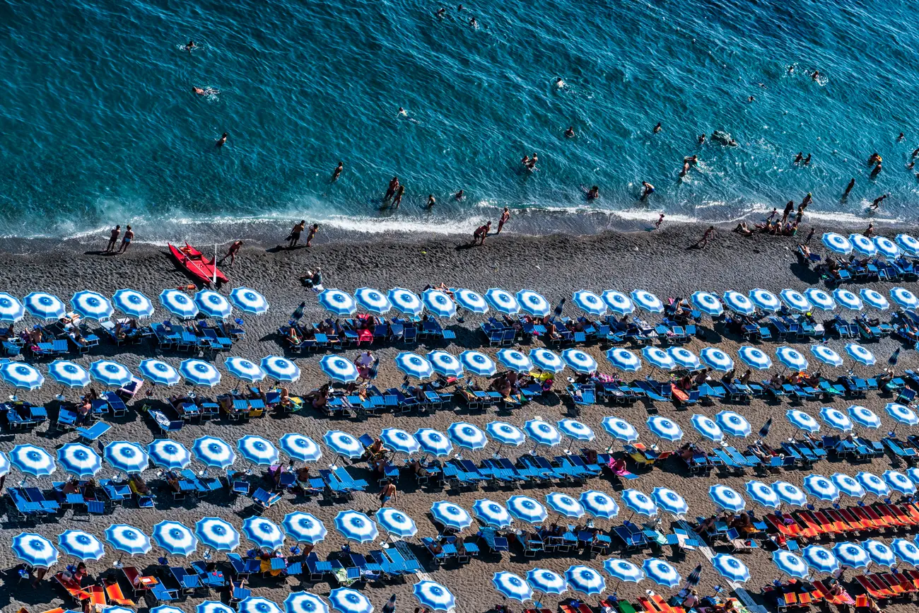 Beach umbrellas and swimmers along Positano's shoreline