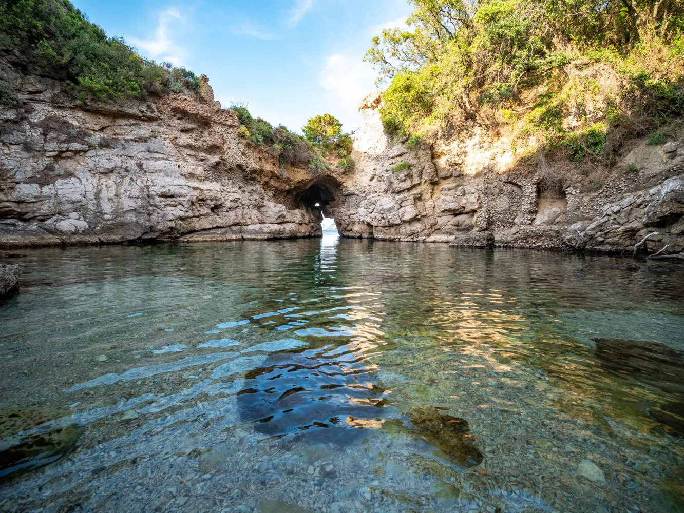 The rocky natural pool at Bagni della Regina Giovanna with a low arch opening to the sea